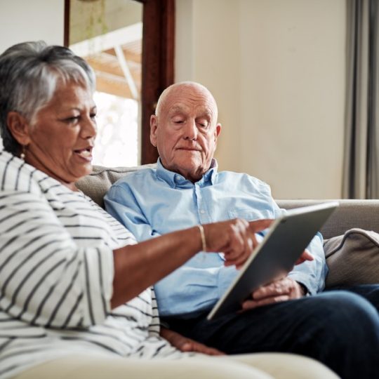 elderly couple on couch with a tablet