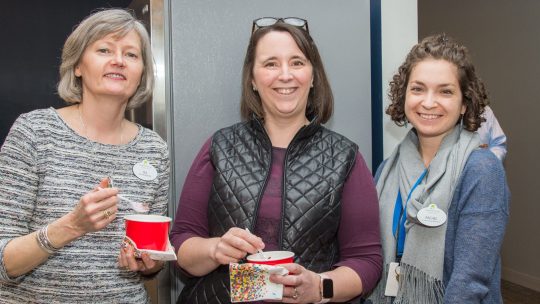 Three staff members with drinks and snacks