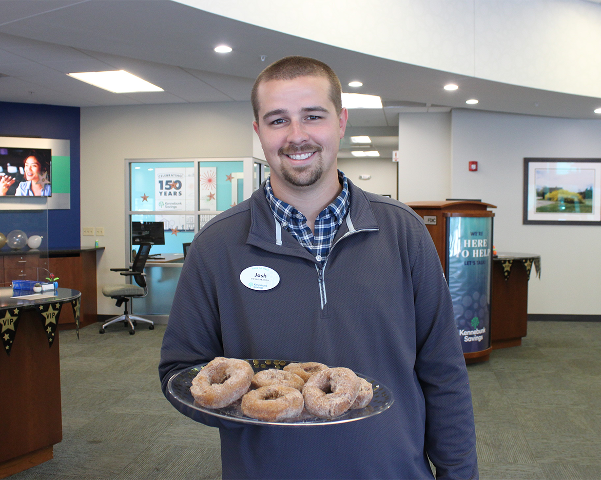 A bank employee holds a plate of donuts for customers to take