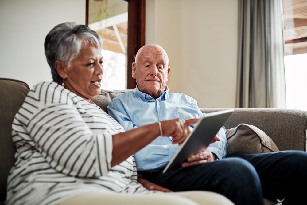 elderly couple on couch with a tablet